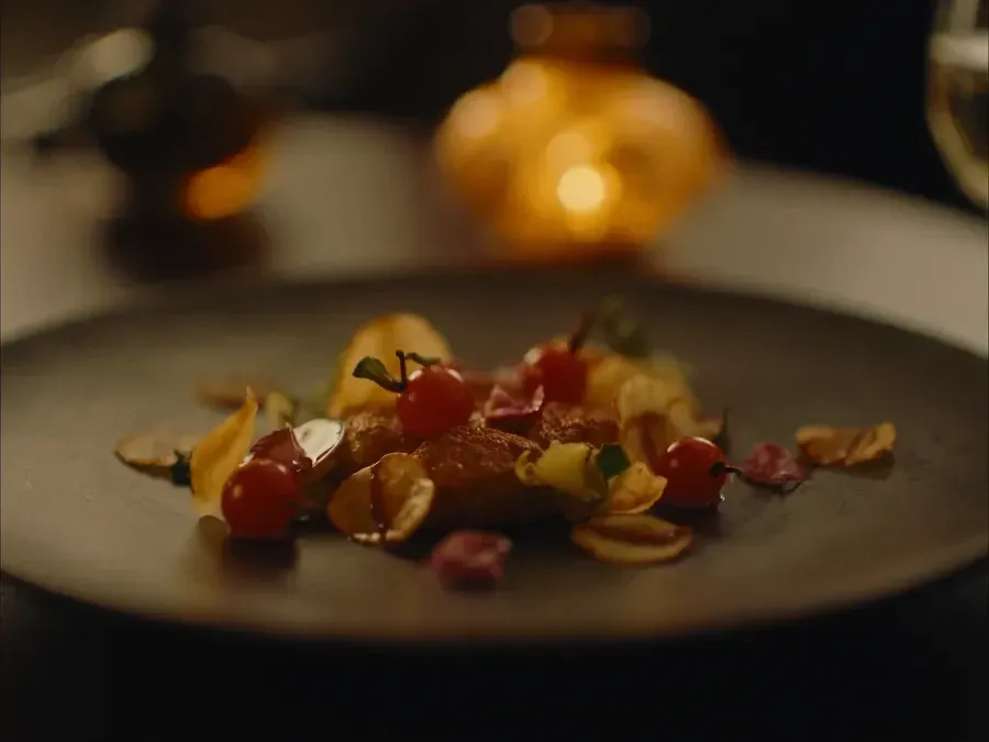A plated dish with cherry tomatoes, lit by a table lamp.